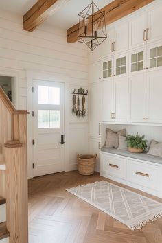 a white kitchen with wooden floors and cabinets in the corner, along with a rug on the floor