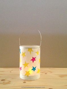 a lit candle holder sitting on top of a wooden table with stars painted on it