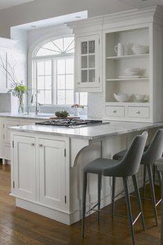 a kitchen with white cabinets and gray chairs