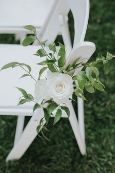 a bouquet of white flowers sitting on top of a white chair with green leaves around it