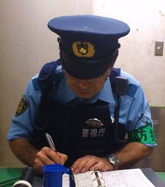 a police officer writing on a piece of paper while sitting at a table with other items