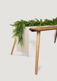 a wooden table topped with green plants and a white cloth draped over the top of it