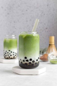 two glasses filled with green liquid on top of a table