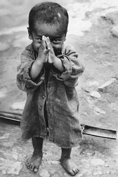 a little boy standing on the ground with his hands in front of his face and eyes closed