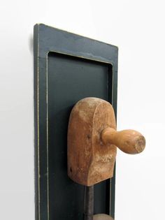 an old wooden tool is hanging on the wall next to a black frame with a hammer in it