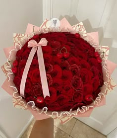 a large bouquet of red roses in a pink paper wrapper with a bow on it