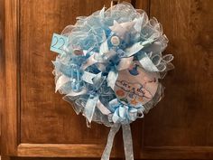 a blue and white baby wreath hanging on a wooden door with it's birth date