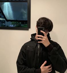 a young man taking a selfie in front of a mirror with his cell phone