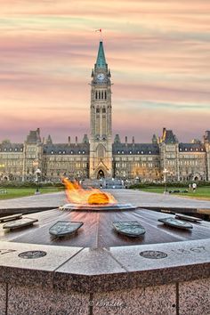 a fire pit in front of a large building with a clock tower on it's side