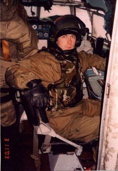 a man sitting in the cockpit of an airplane wearing a helmet and holding a glove