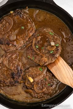 steaks and mushrooms cooking in a skillet with a wooden spoon