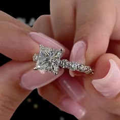 a woman's hand holding a diamond ring with pink manies on her nails