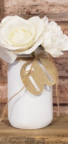 a white vase filled with flowers on top of a wooden table