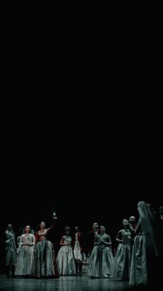 a group of people standing on top of a stage in dresses and headdresses