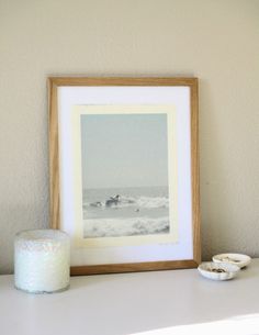 a framed photograph sitting on top of a white table next to a roll of toilet paper