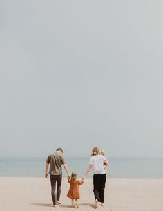 a family walking on the beach holding hands