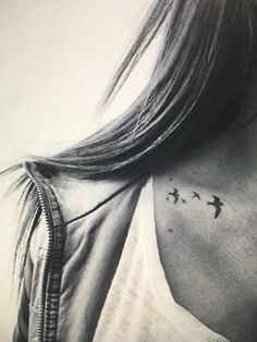 black and white photograph of woman with birds tattoo on her upper back shoulder, looking to the left