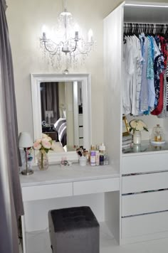 a white dressing table with drawers and a chandelier hanging from it's ceiling