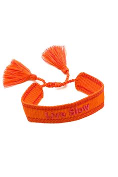 an orange bracelet that says, we're evil with tassels on it