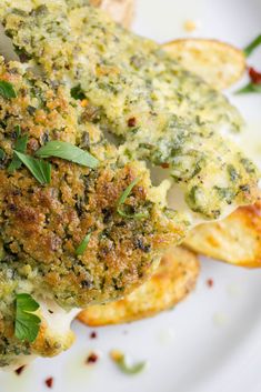 a white plate topped with broccoli covered in cheese and sauces next to potato wedges