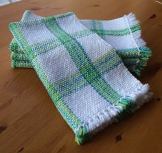 two green and white towels sitting on top of a wooden table next to each other