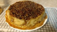 a cake sitting on top of a white plate covered in pecan flakes and topped with caramel