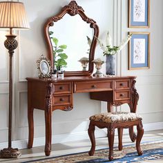 an ornate wooden vanity table with mirror and stool in a living room next to a lamp