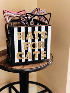 a black and white box that says hats for cats sitting on top of a stool