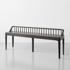 a wooden bench sitting on top of a white floor in front of a gray wall