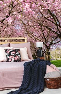 a bedroom with pink flowers on the wall and bed in the foreground, next to a basket full of pillows