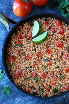 a pan filled with rice, tomatoes and cilantro on top of a table