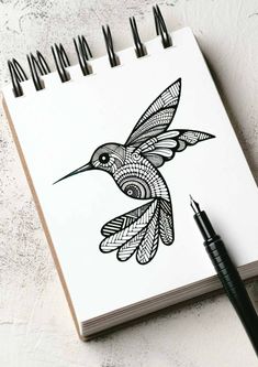 a notebook with a drawing of a hummingbird on it and a pen next to it