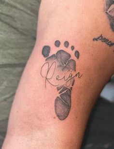 a person with a tattoo on their arm that reads reign and has an image of a dog's paw