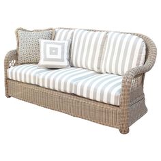 a wicker couch with blue and white striped pillows on it's armrests