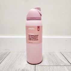 a pink water bottle sitting on top of a wooden floor next to a white wall