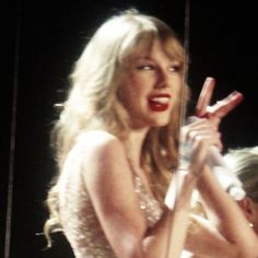 a woman holding a microphone in her right hand and wearing a dress with sequins on it