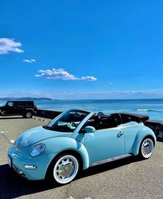 a blue convertible car parked next to the ocean