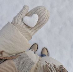 someone wearing mittens and gloves with a white heart on their thumb, standing in the snow