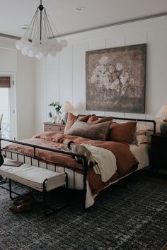 a bedroom with a large bed, chair and painting hanging on the wall above it