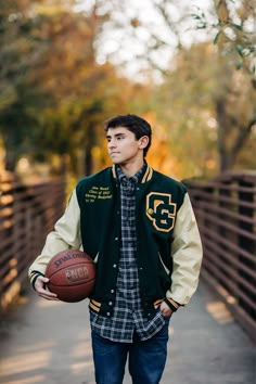 a young man is holding a basketball while standing on a bridge with trees in the background