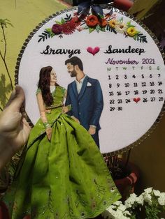 a hand holding up a personalized photo on a calendar ornament for a wedding