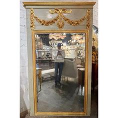 a man standing in front of a large mirror with gold trimmings on it