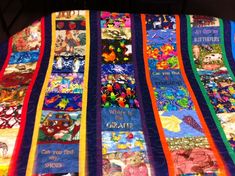 there is a very large colorful quilt on the table top that has pictures and words on it