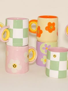 several colorful cups are stacked on top of each other, with flowers painted on them