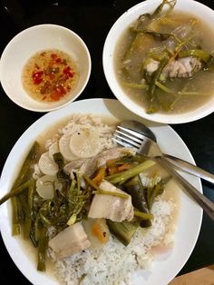 two white bowls filled with rice, meat and veggies on top of a table