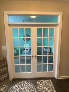 the inside of a room with two doors and a rug on the floor in front of it