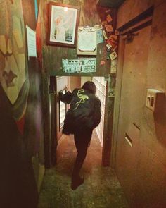 a person is walking down an alley way with a backpack on their back and some posters above them