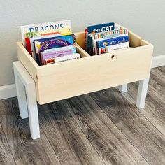 a wooden toy box filled with books on the floor