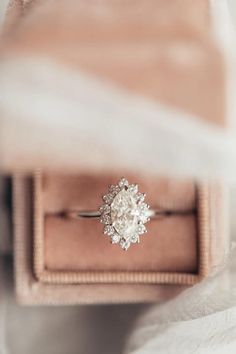 an engagement ring sitting on top of a velvet box