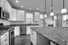 a large kitchen with granite counter tops and white cabinets, along with stainless steel appliances